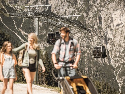 Ein Mann, eine Frau und ein Kind beim wandern, dahinter sind die Gondeln zu sehen von Ladurns