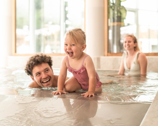 Tochter spielt mit ihrer Familie im Babypool im familienhotel südtirol mit wasserrutsche