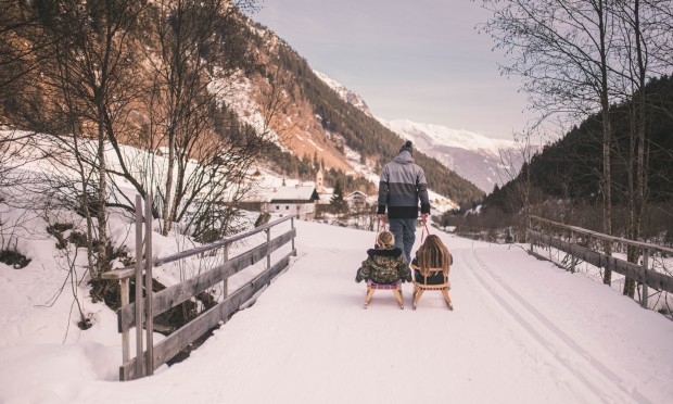 Vor dem Feuerstein zieht ein Vater seine Kinder auf der Rodel.
