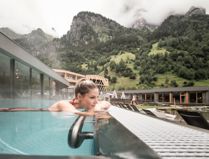 Eine Frau genießt den Infinity-Außenpool in einem Familienhotel mit Wasserrutsche in Südtirol.