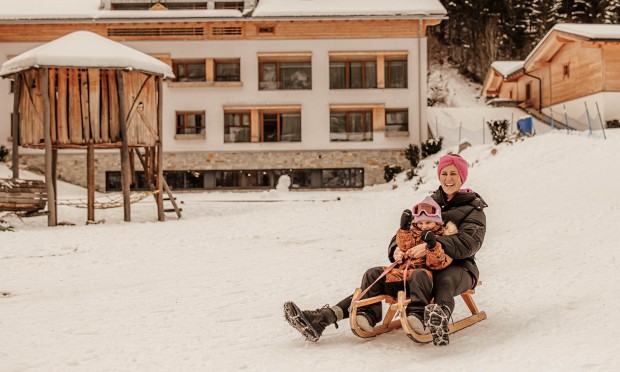 Mutter und Tochter rodeln im Feuerstein Garten den Hang hinunter.