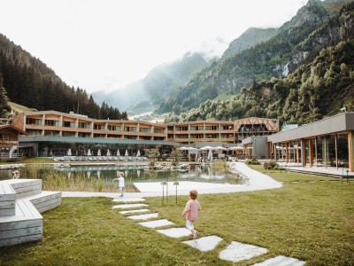 die Sonne strahlt und wir sehen den Badeteich und dahinter das Feuerstein Nature Family Resort strahlen