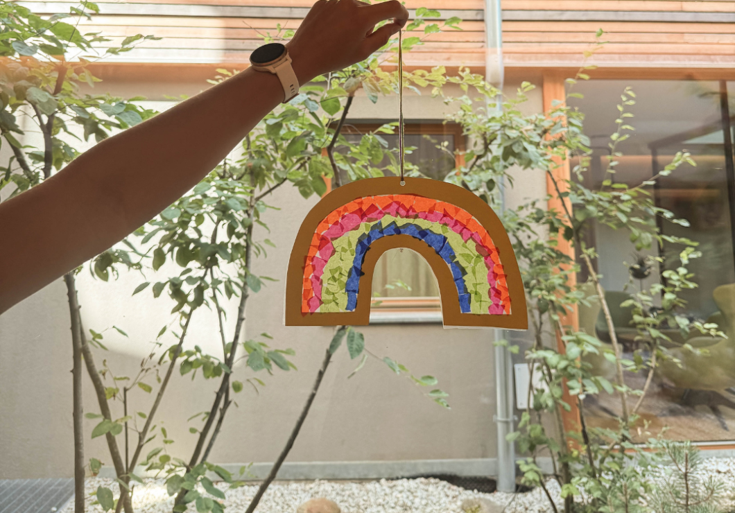 Selbergemachter Regenbogen der am Fenster hängt und schön leuchtet.