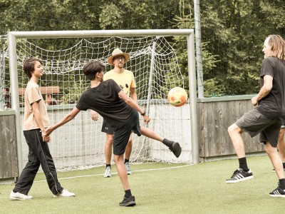 1 Mann mit 2 Jungs und Kinderbetreuer beim Fussballspielen