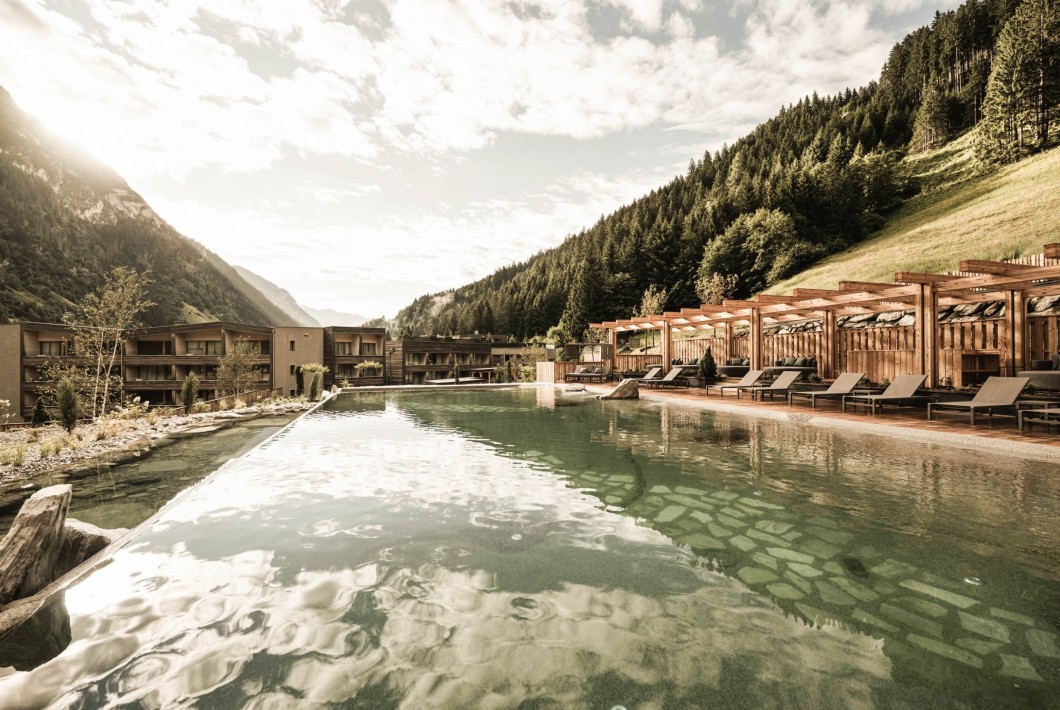 Neuer in unserem Wellnessprogramm beheizter Schwimmsee mit Blick auf die Berge und Hotel
