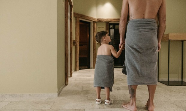 Vater und Sohn sind am Weg zum Familienwellness und in die Familiensauna im Feurstein Nature Family Resort