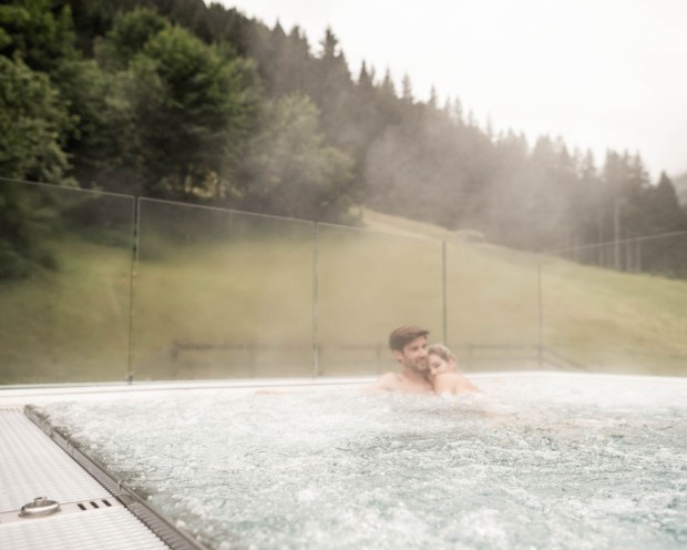 Ein Pärchen genießt Paarzeit auf der Adults Only Dachterasse im Whirlpool.