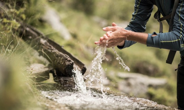 Frau wascht sich die Hände mit Quellwasser