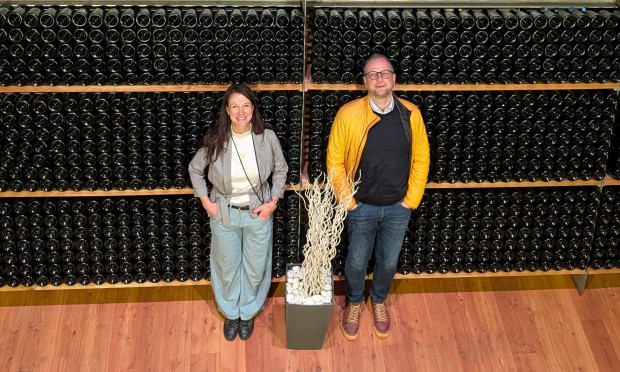 Direktorin Julia Auckenthaler und Vizedirektor Massimo stehen vor einem großen Weinregal.