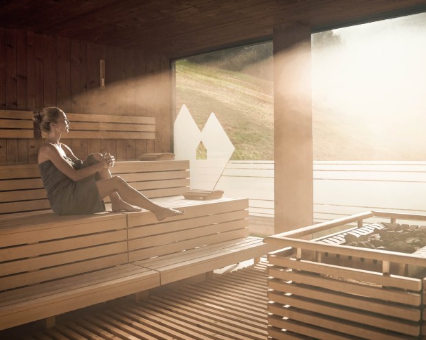 Eine Frau geniesst die finnische Sauna im Familienhotel mit Wasserrutsche in Südtirol.
