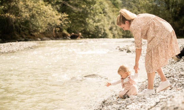 Mutter spaziert mit Kind entlang des Fluss