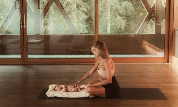 Mutter sitzt auf Boden und spielt mit ihrem Baby