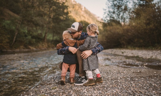 Vater umarmt hockend seine zwei Kinder
