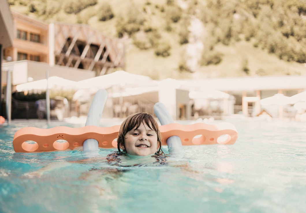 A girl is swimming in the pool with a swimming aid and learning to swim.