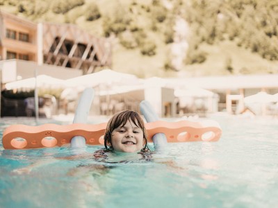 A girl is swimming in the pool with a swimming aid and learning to swim.