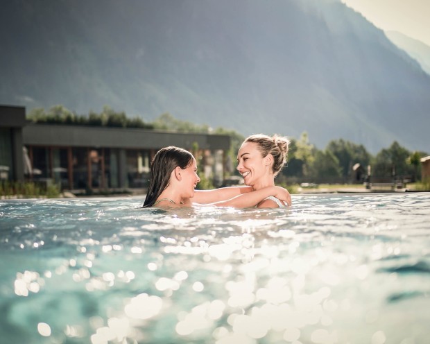 Eine Mutter und ihre Tochter spielen im Außenpool eines Kinderhotels in Südtirol.