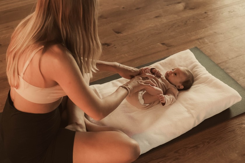 Mutter mit liegendem Baby im Yoga Raum