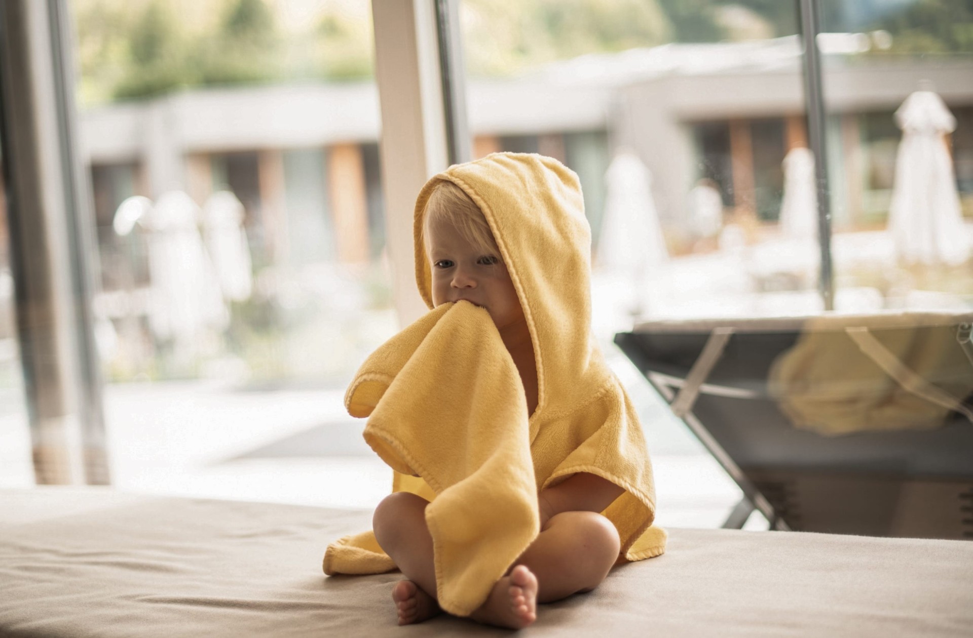 Kleines Kind sitzt mit einem gelben Bademantel