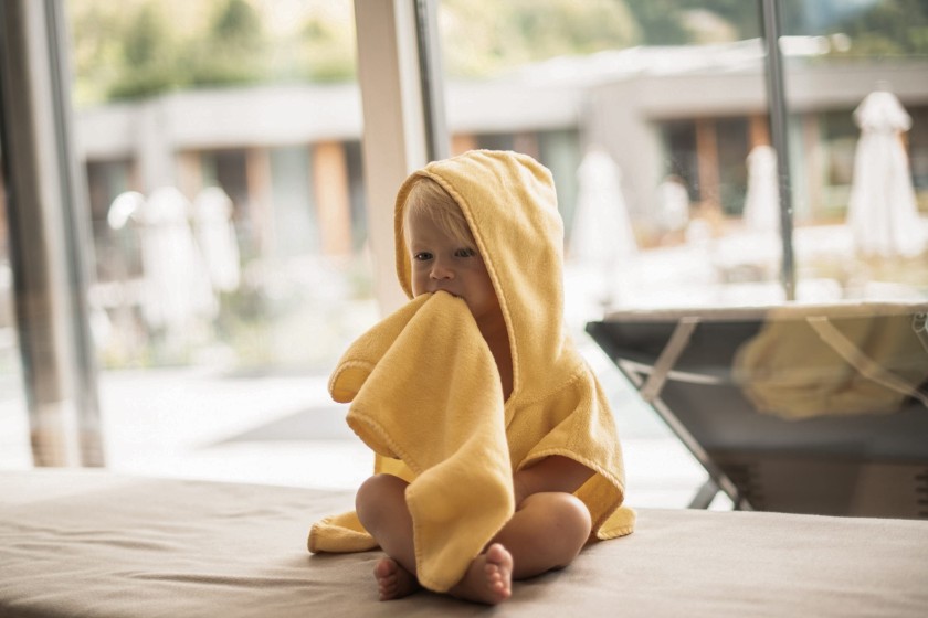 Kleines Kind sitzt mit einem gelben Bademantel