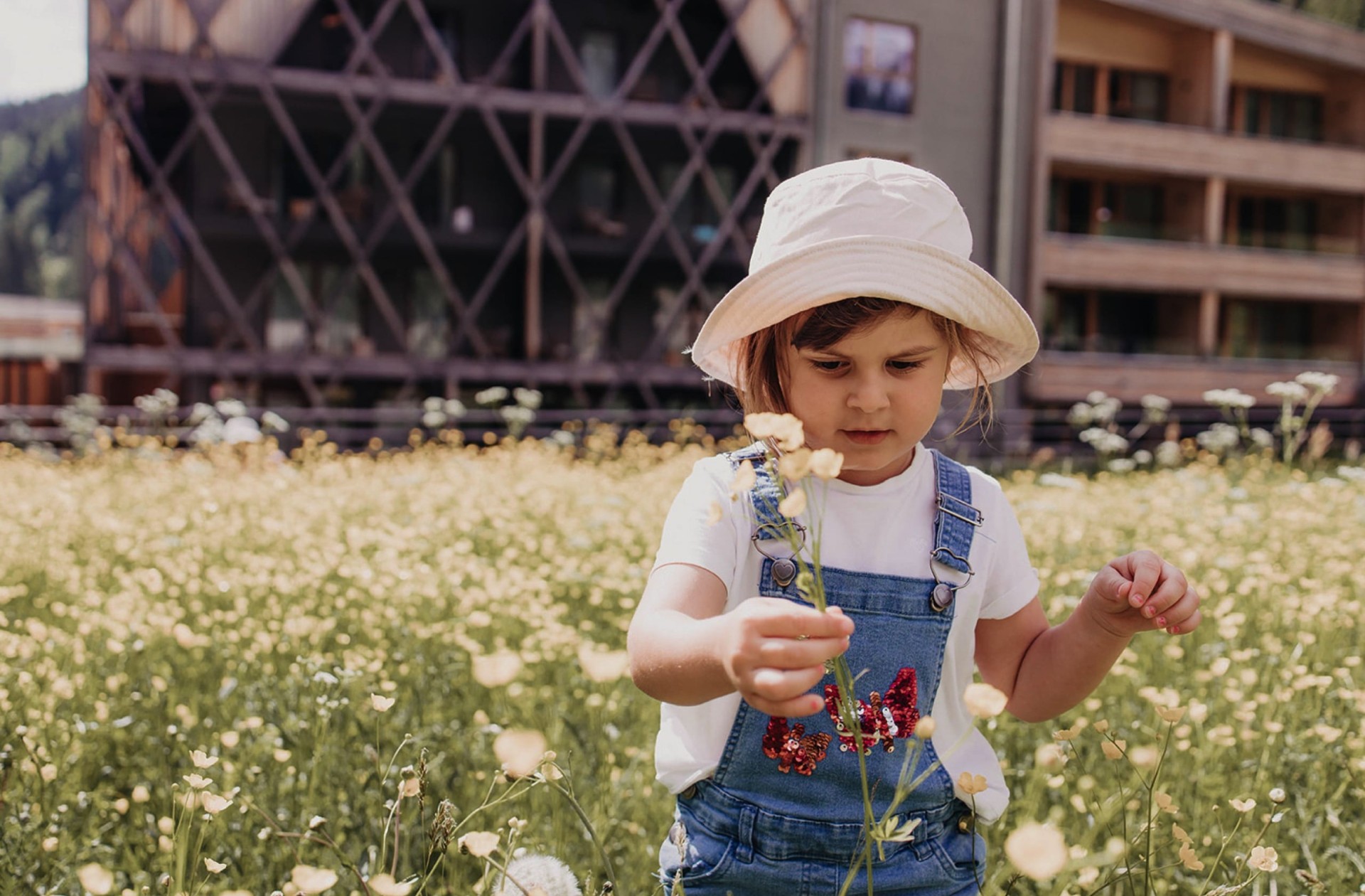 Bambina con cappello cammina tra i fiori di un prato al Feuerstein.