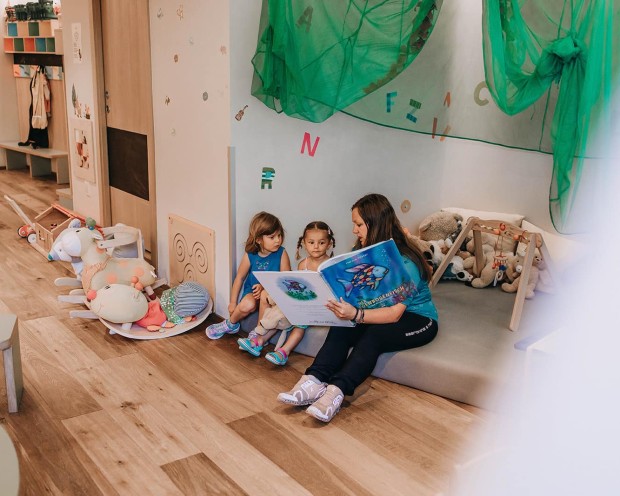 Betreuerun liest den Kindern ein Buch vor