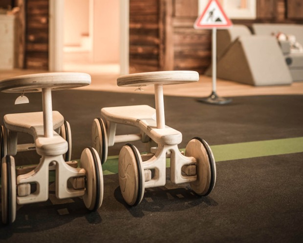 2 Holzautos vor ein begehbaren Puppenhaus