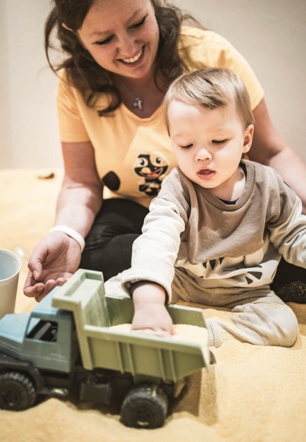 Il figlio di Kleien gioca con i camion nella sabbiera.