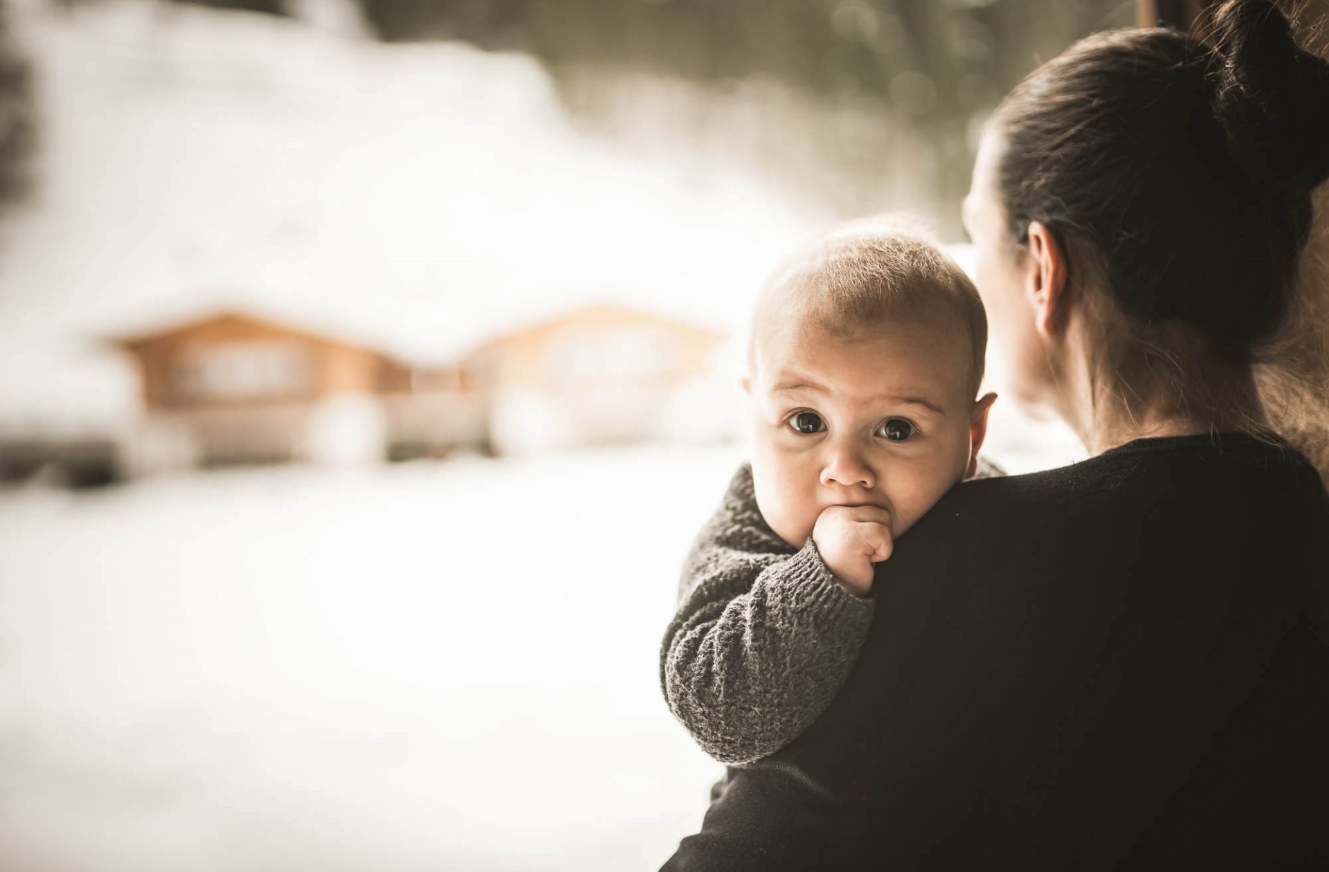 Baby wird von Mutter gehalten und steht am Fenster