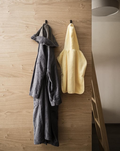 Bademantel eines Kindes hängt neben den eines Erwachsenen