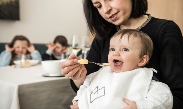 Eine Familie sitzt gemütlich beisammen, während ein Kind eine kleine Tasse hält.
