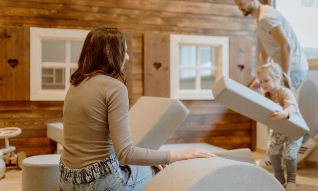 Kinder und Erwachsene spielen gemeinsam mit großen weichen Bausteinen in einem Spielbereich.