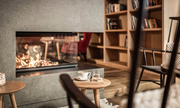 Stühle und Bücherregal mit Kaffeetasse vor dem Kaminfeuer