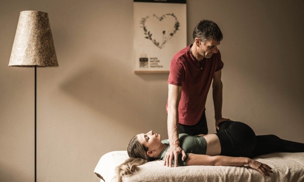 Ein Therapeut führt eine tiefgehende Druckmassage an einer liegenden Person durch.