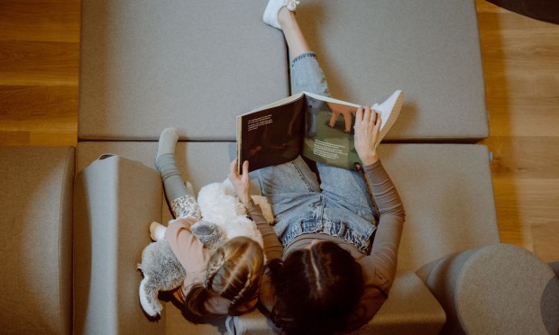 Ein Kind liegt entspannt auf weichen Kissen und liest ein Buch.