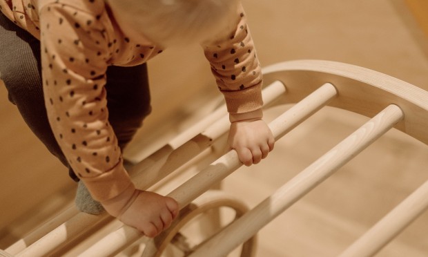 Kleinkind klettert Holzgerüst hinauf