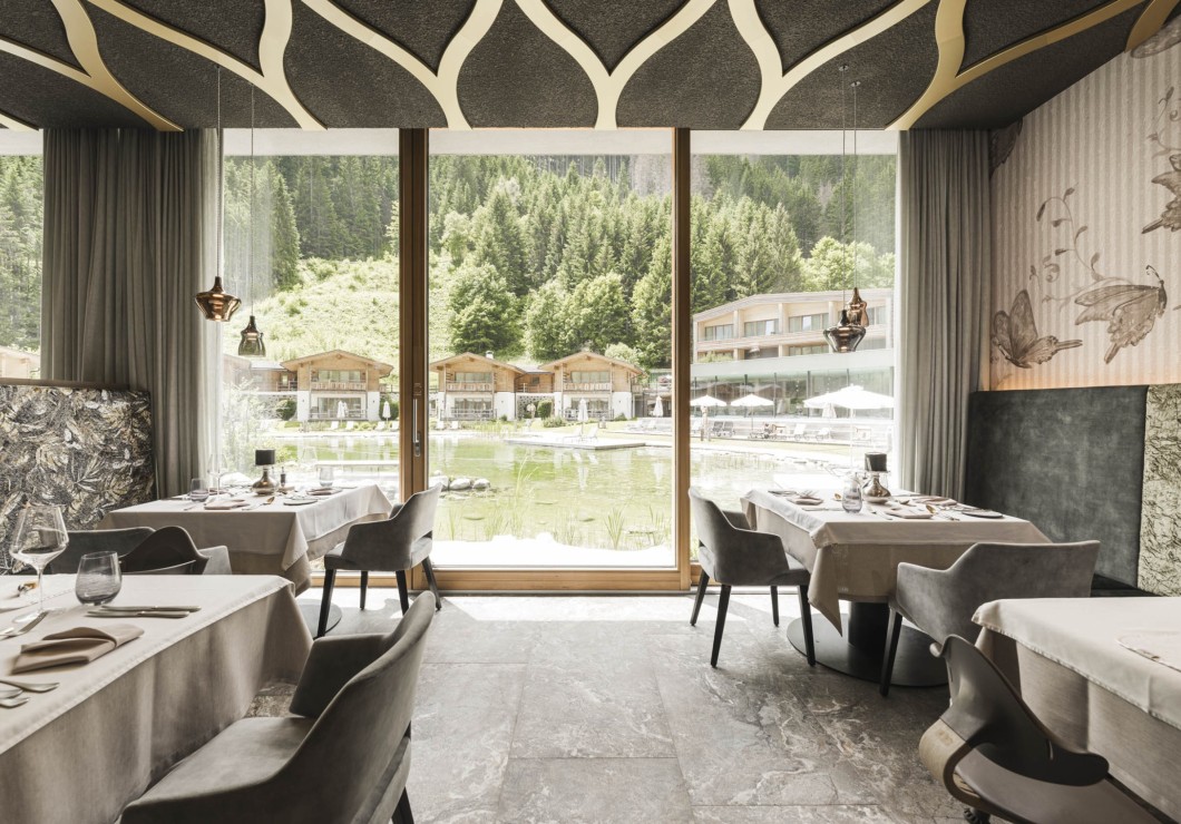 Ein heller, moderner Speisesaal mit großen Glasfenstern und Blick auf die Natur.