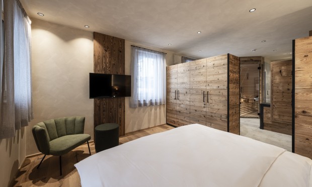 Ein elegantes Schlafzimmer mit Holzakzenten, großem Bett und Sitzbereich.