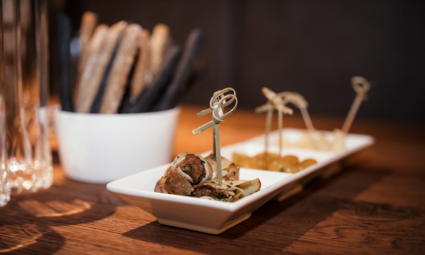 Eine edle Auswahl an Fingerfood auf einem Holztisch mit stilvoller Beleuchtung.