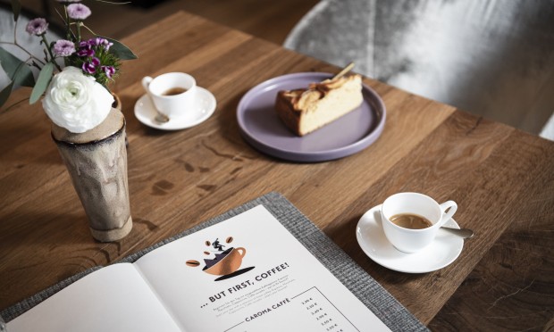 Ein liebevoll arrangierter Frühstückstisch mit Kaffee, Gebäck und einem Buch.