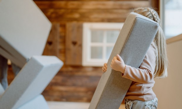 Ein Kind hebt eine große Schaumstoffbaustein auf, um eine kreative Struktur zu bauen.