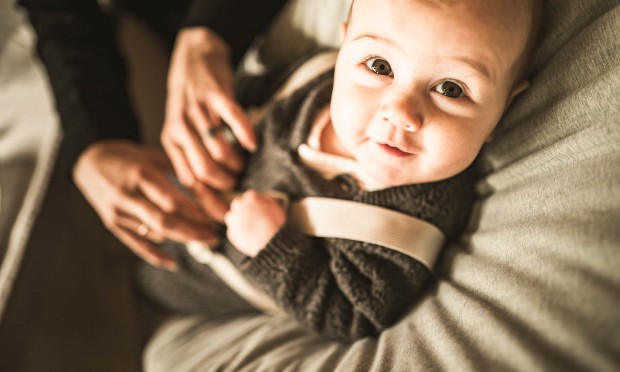 Ein Baby schaut neugierig in die Kamera, während es in den Armen gehalten wird.