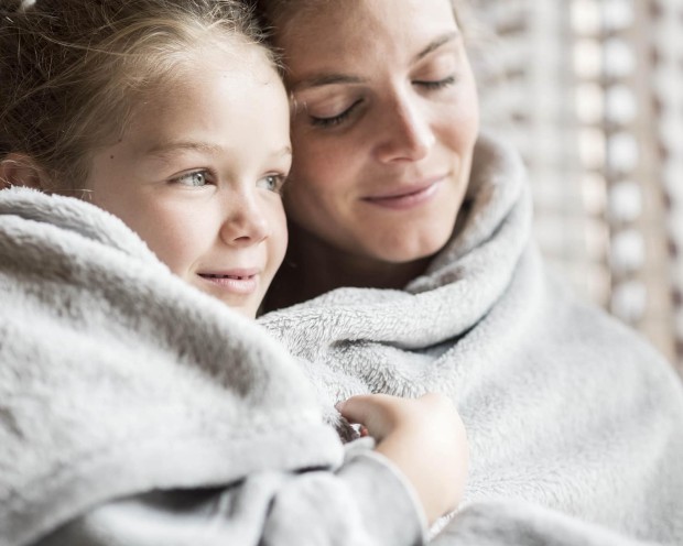 Tochter mit Mutter eingewickelt in einer Decke