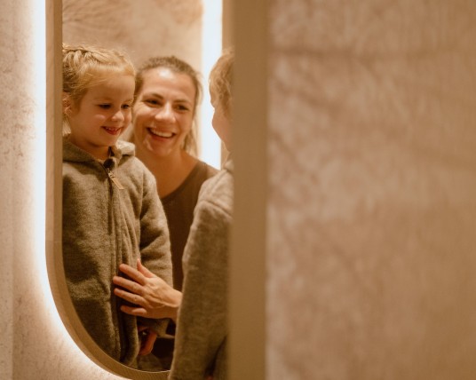 Kind mit Mutter schauen in den Spiegel und bewundern neues Outfit im Feuerstein Concept Store
