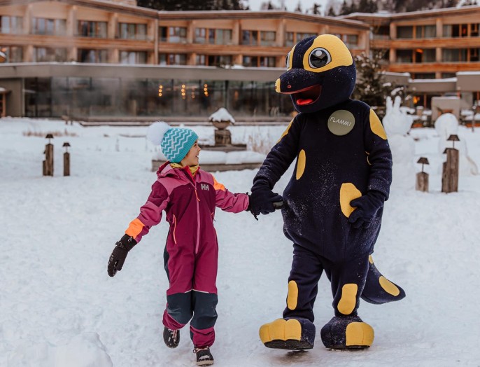 Mädchen mit Maskottchen Flammi im Familienhotel Feuerstein in Südtirol