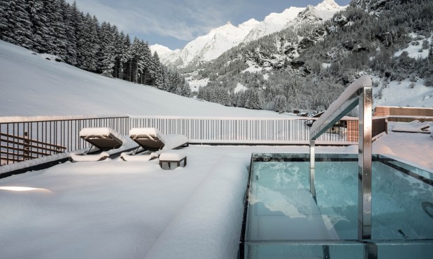 Ein beheizter Outdoor-Pool mit Blick auf eine verschneite Berglandschaft.