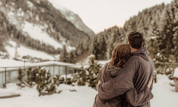 Ein Paar steht in einer winterlichen Umgebung und schaut gemeinsam in die Ferne.