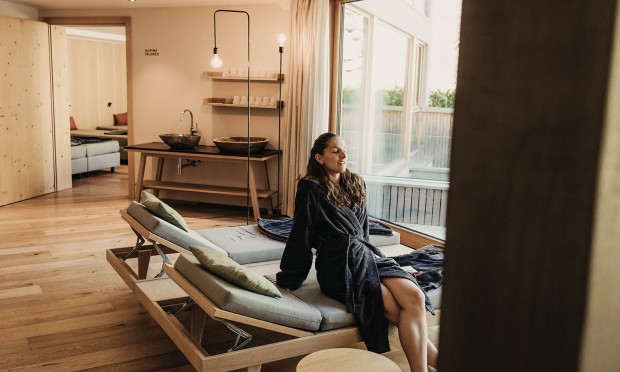 Eine Frau entspannt auf einer Liege in einem stilvollen Spa-Bereich.