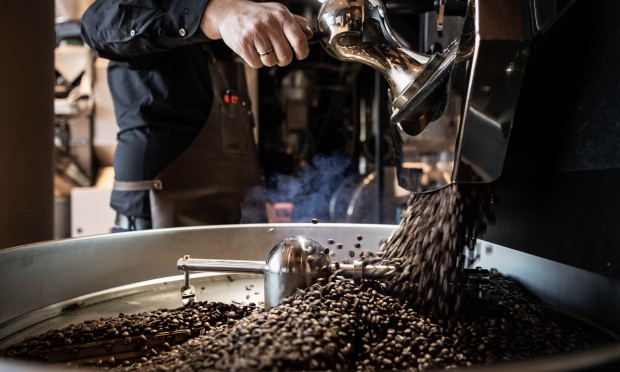 Ein Röstmeister arbeitet an einer Kaffeeröstmaschine.