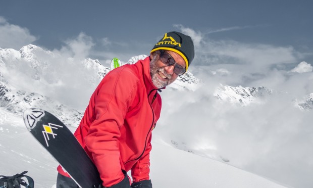 Skitourengeher hält ein Ski in der Hand inmitten des schneebedeckten Berges