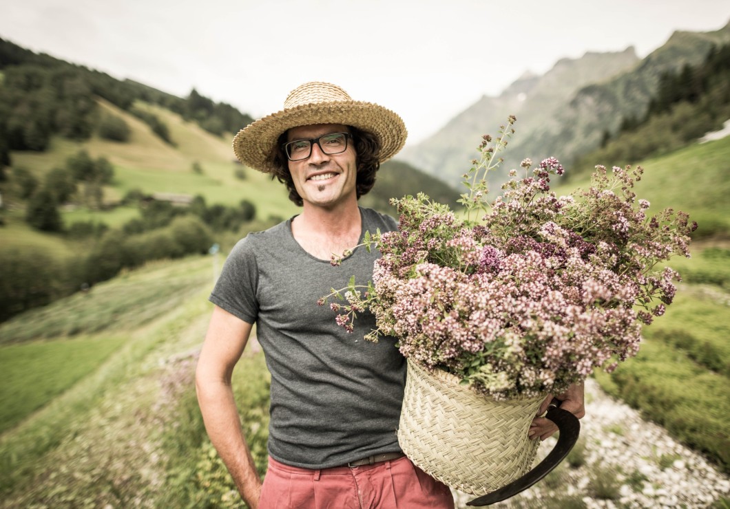 Person im Kräuterfeld und Korb voller Kräuter